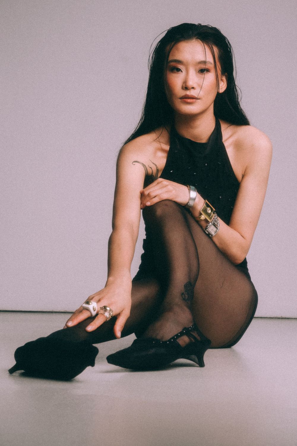 Artistic portrait of dancer in black outfit sitting on floor.