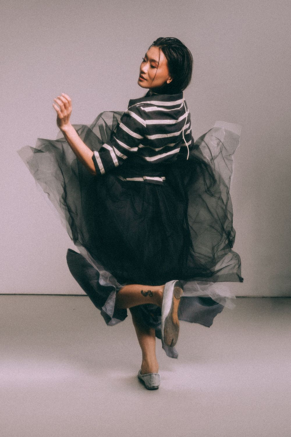 Dancer twirls in striped top and flowing tulle skirt during studio performance.
