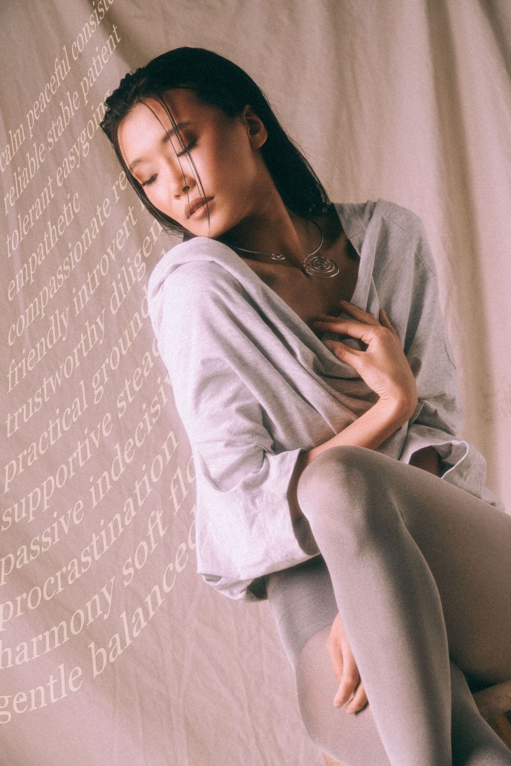 Ethereal studio portrait with overlaid text and soft gray fabric draping.