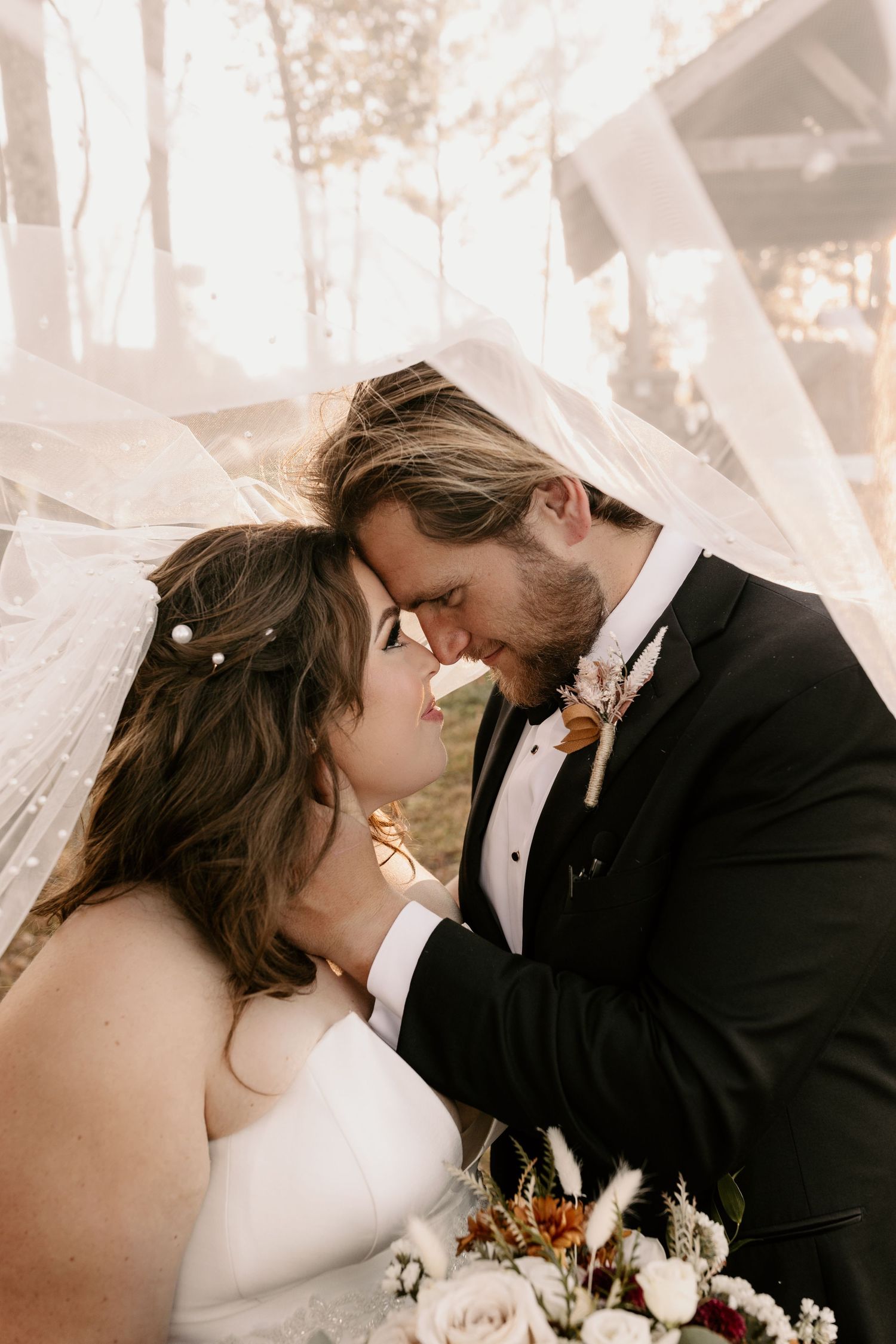 A romantic moment under a flowing veil as newlyweds share an intimate kiss.