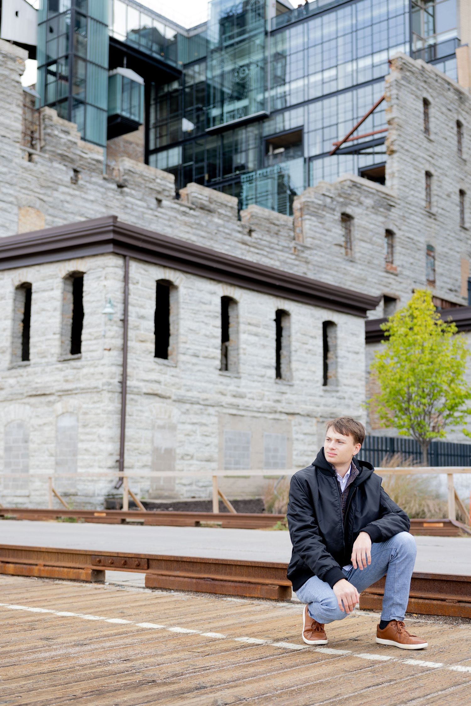 Modern glass building contrasts with historic stone fortress architecture on wooden deck.