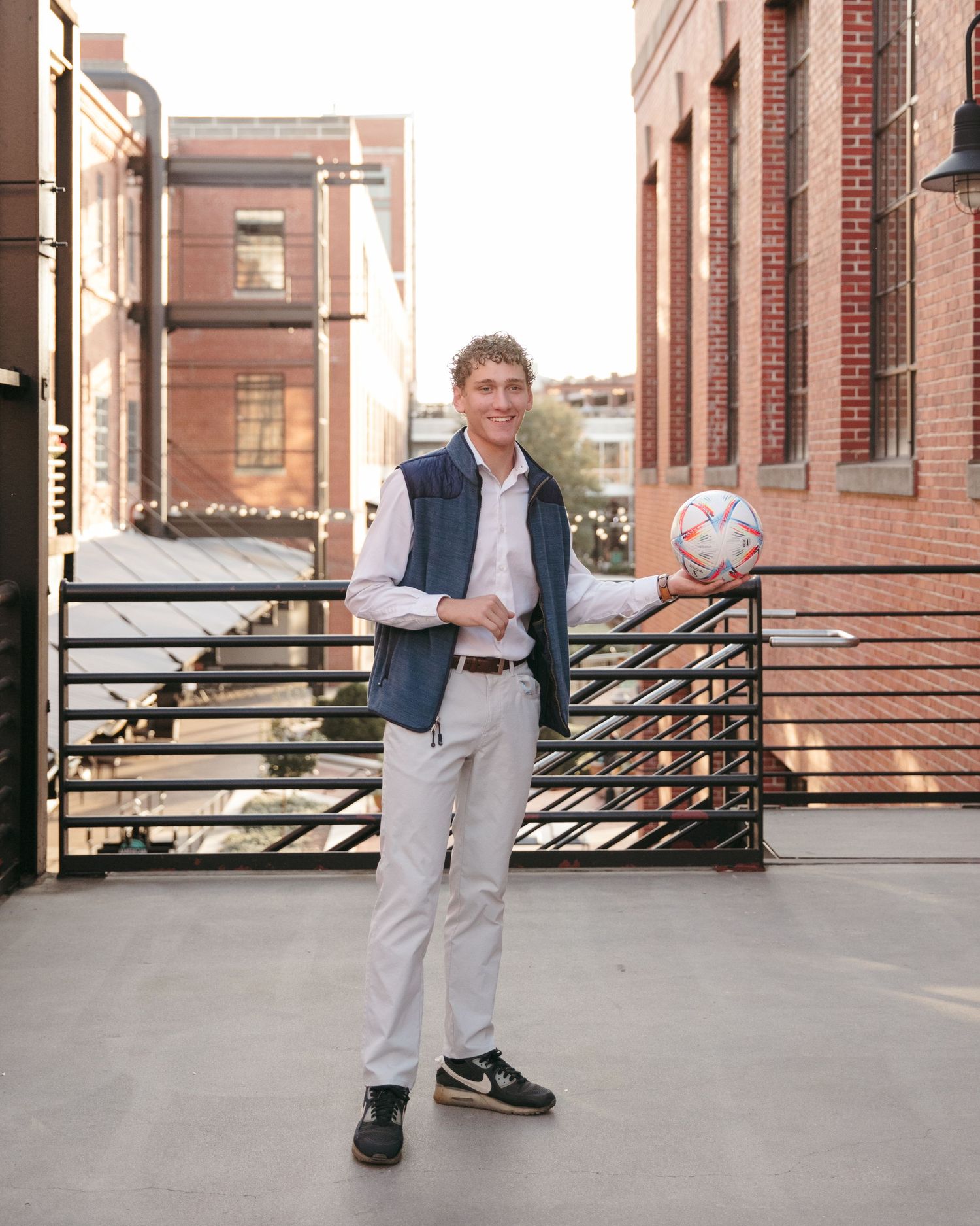 Child posing on an urban rooftop against brick buildings in formal attire.