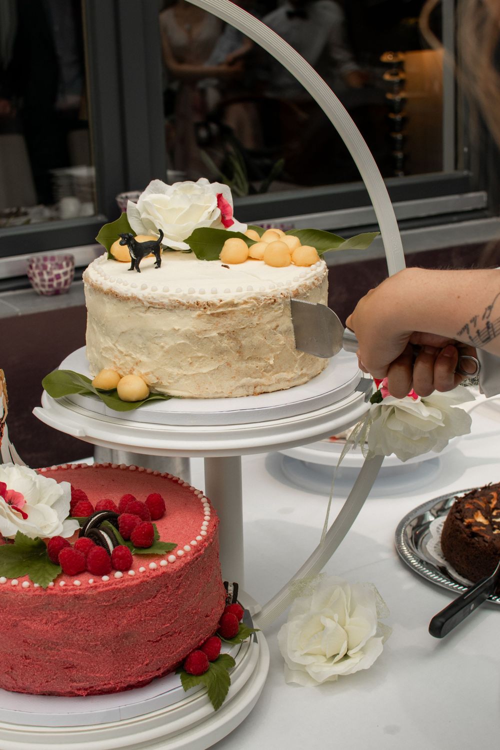 Display of elegant wedding cakes including red velvet and white frosted tiers on decorative stands.