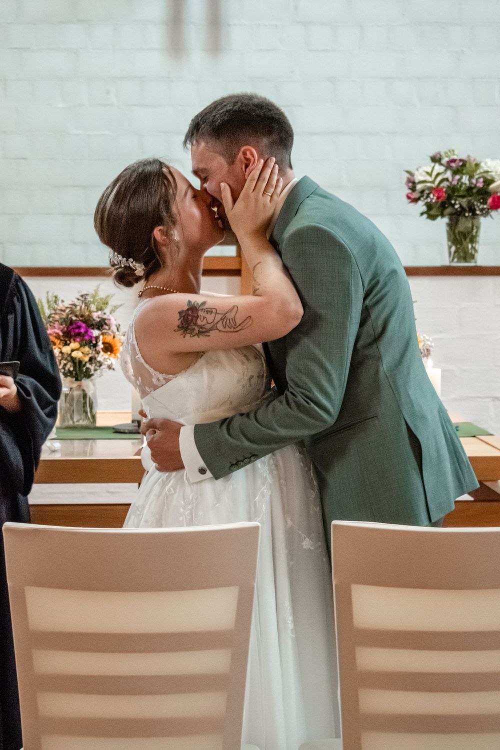 A couple shares a romantic kiss while seated at a piano during their wedding celebration.