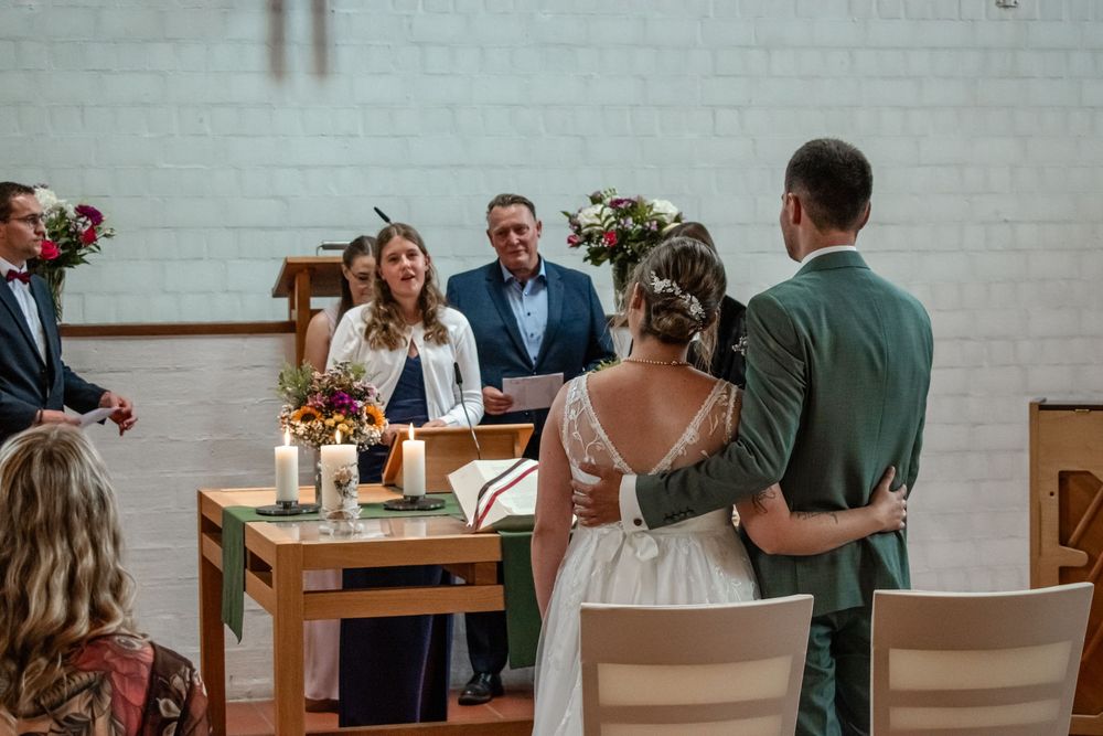Wedding guests gather around tables with floral centerpieces in an elegant white brick venue.
