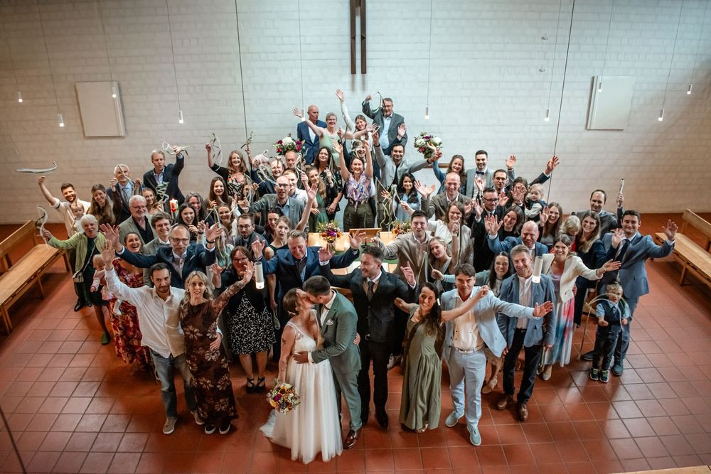 A panoramic sequence of wedding guests posing together in a reception hall with brick walls.