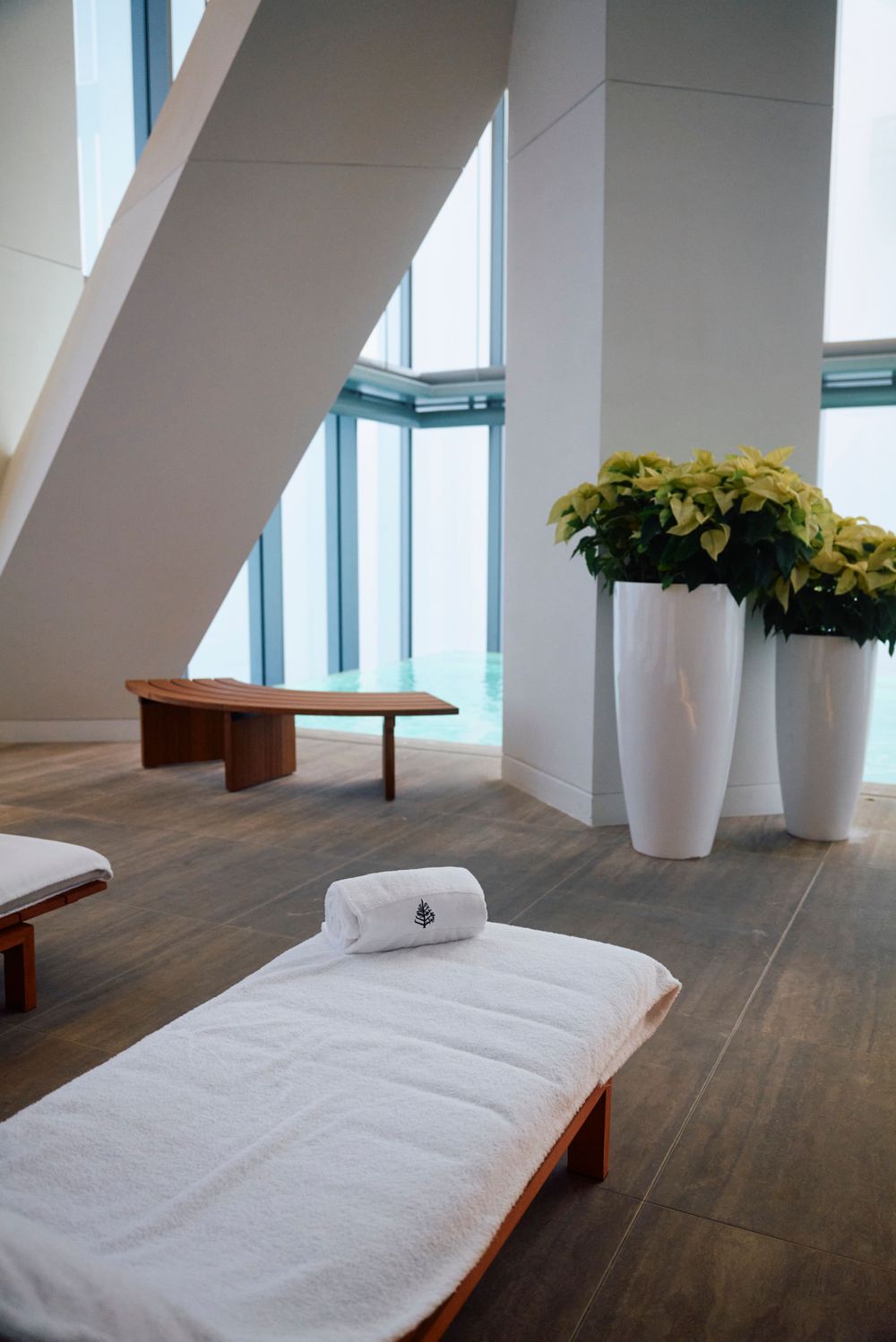 Minimalist spa area with massage tables, white vases filled with yellow flowers, and natural light.