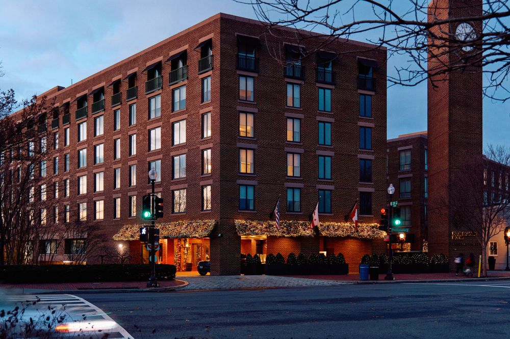 Historic red brick apartment building illuminated at dusk with warm glowing windows and street lights.