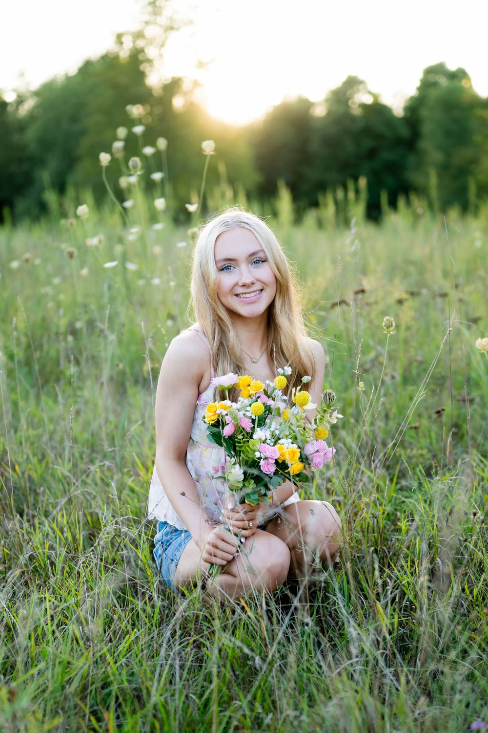 Summer portrait in wildflower meadow at sunset holding colorful bouquet.
