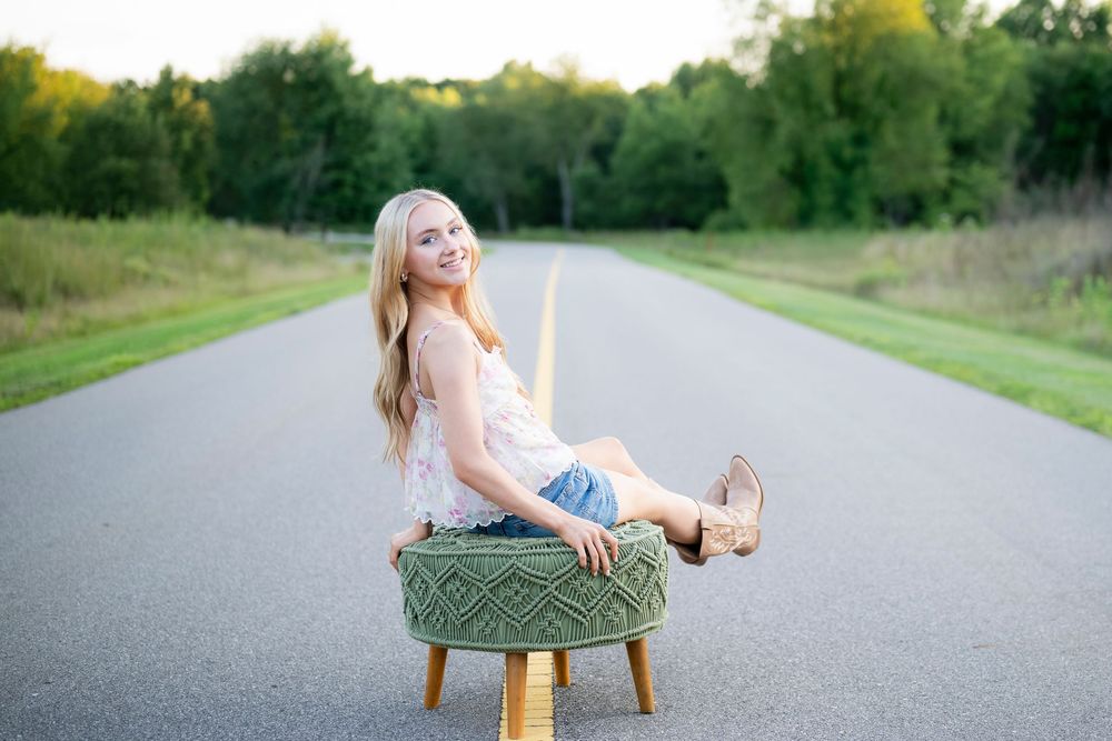 Playful pose on antique stool in middle of country road at sunset.