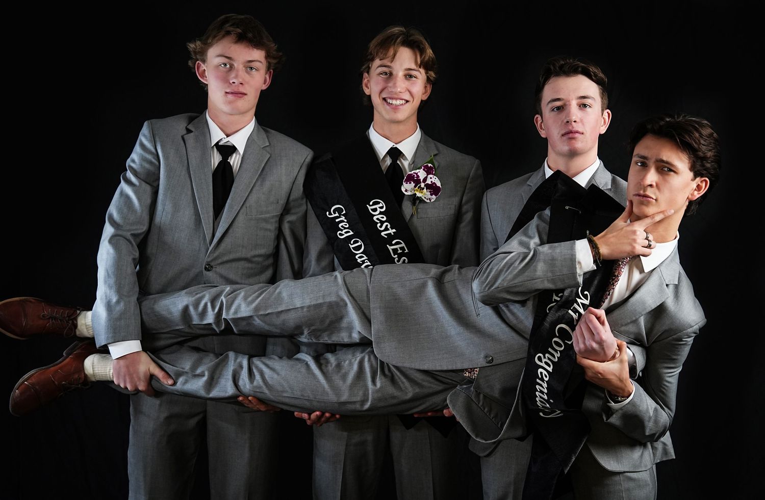 Group of young men in formal wear posing playfully for a photo.