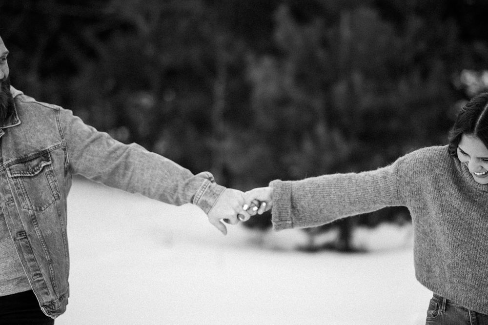Black and white portrait of couple holding hands in winter setting.