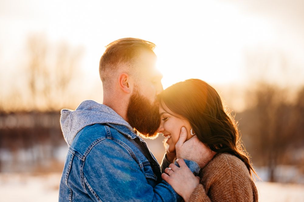 Tender moment between couple in casual winter wear during sunset.