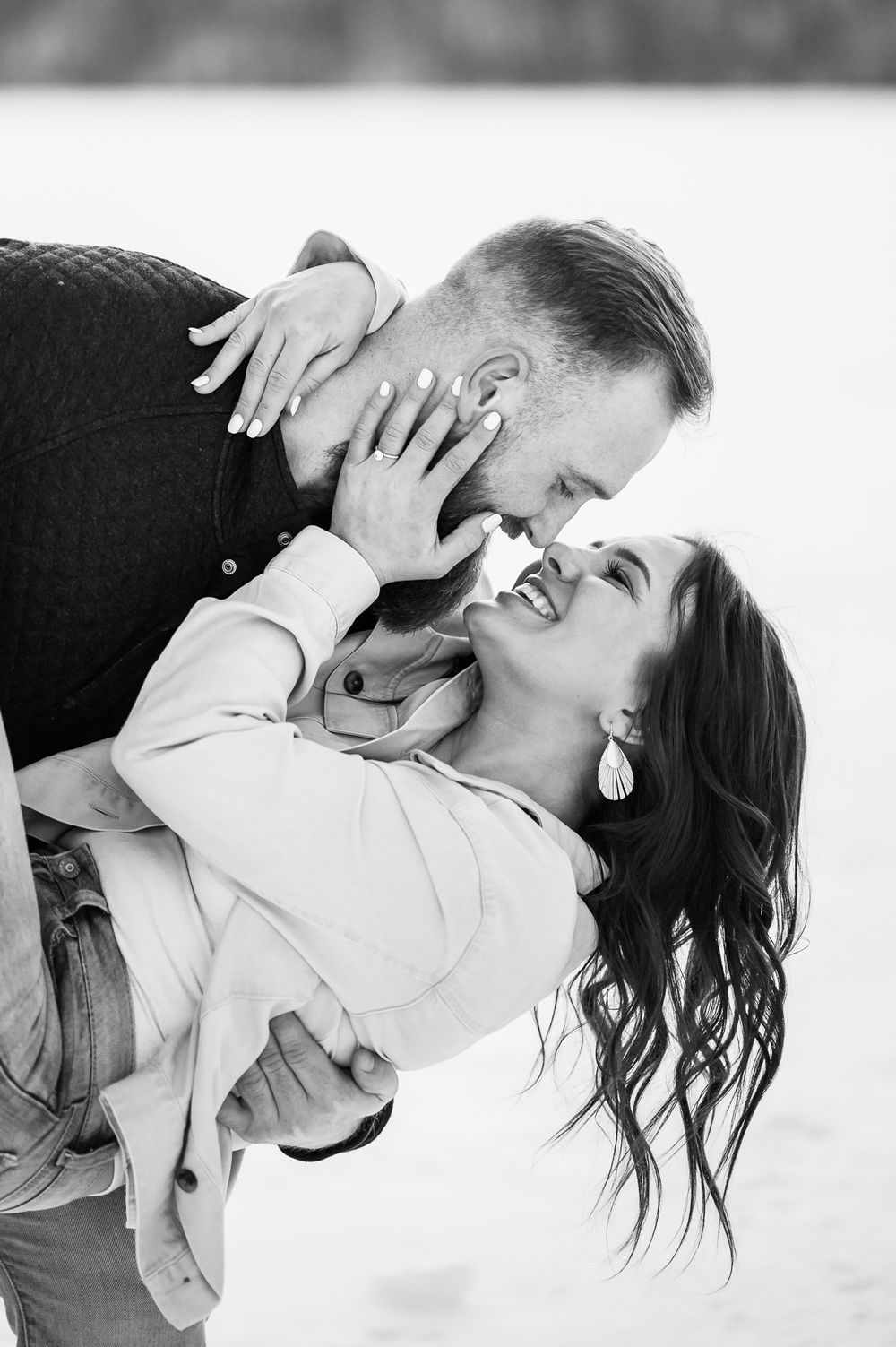 Intimate black and white portrait of a couple sharing a playful moment in winter.