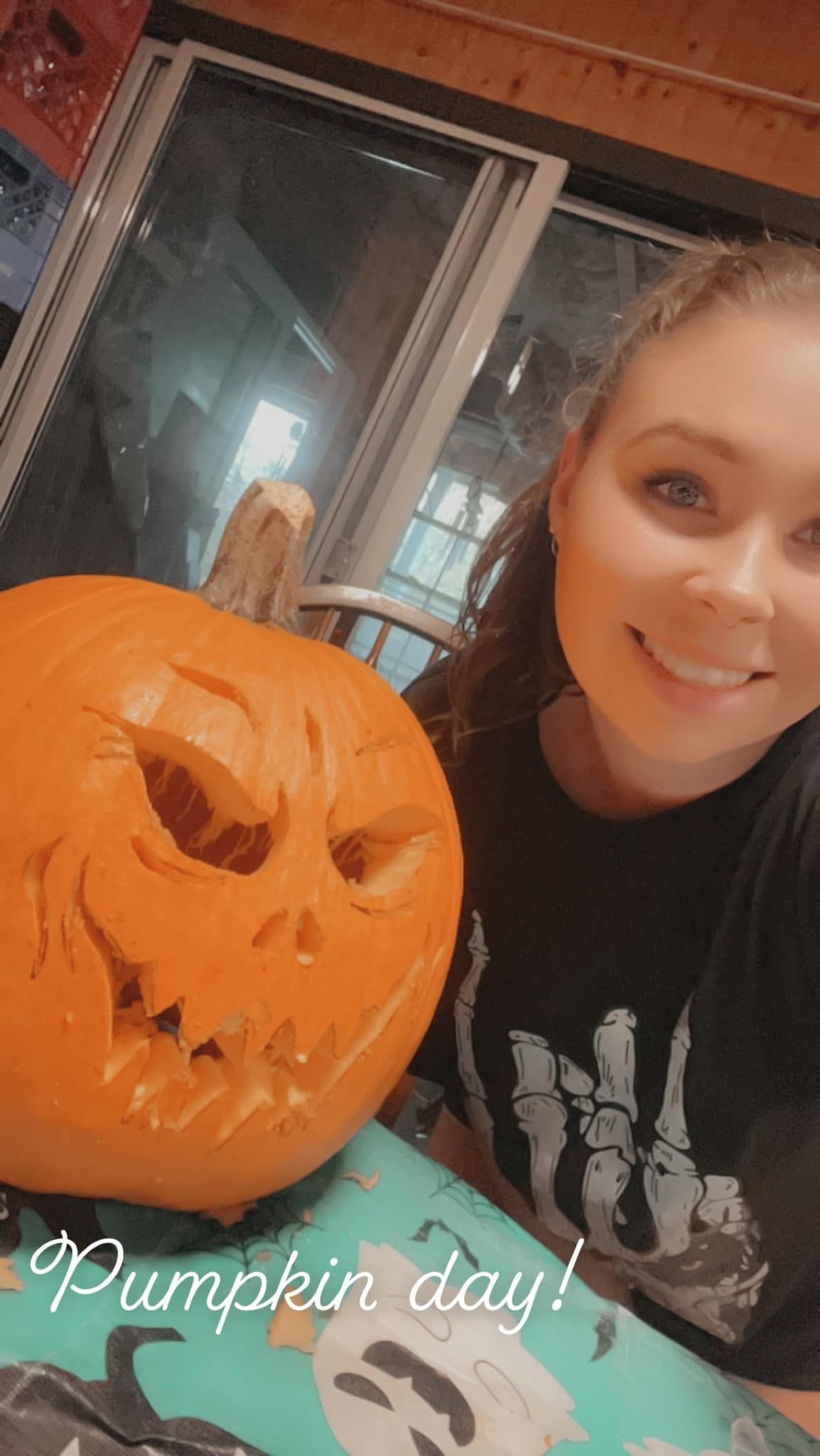A series of carved Halloween pumpkins displayed on a turquoise surface with spooky decorations in the background.