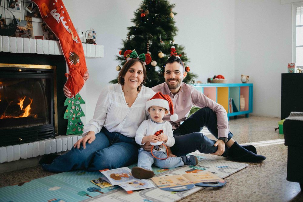 A family sits together on the floor reading books and playing with colorful balloons in a bright living room.