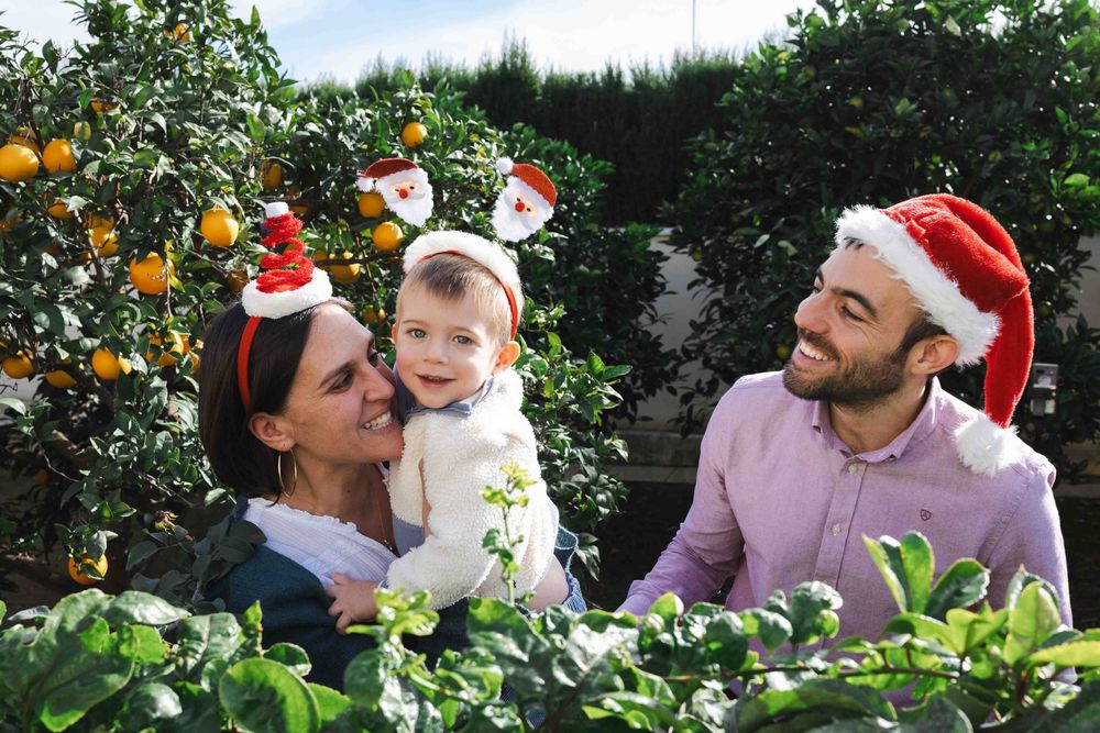 Family enjoying time together in an orange grove during winter while wearing festive holiday attire.