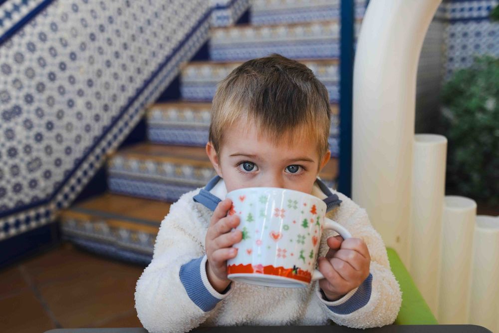A child holds up a colorful paper chain craft showing it off to the camera.