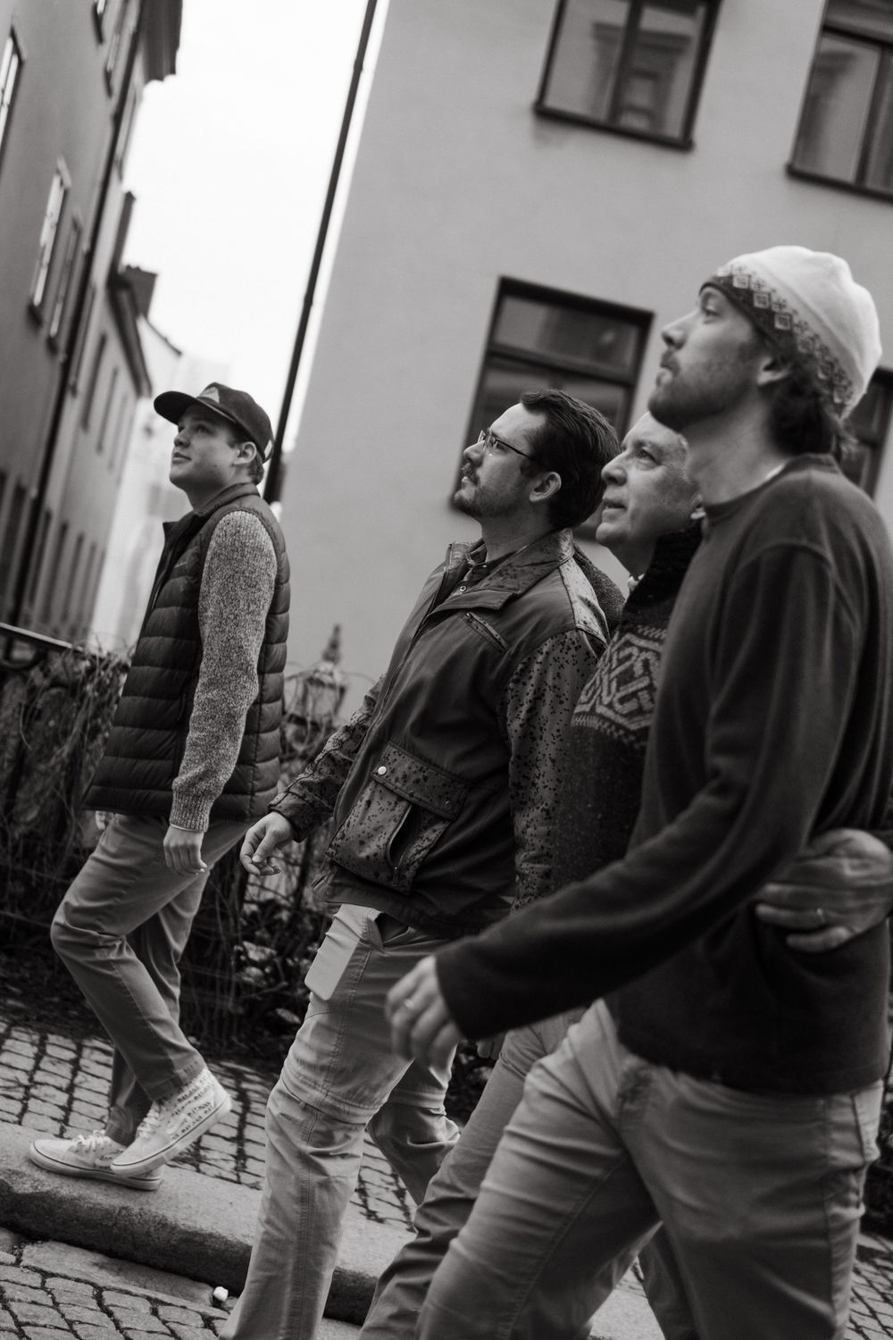 group of brothers walking with their dad through Gamla Stan while being captured by family photographer in Stockholm for vacation photoshoot