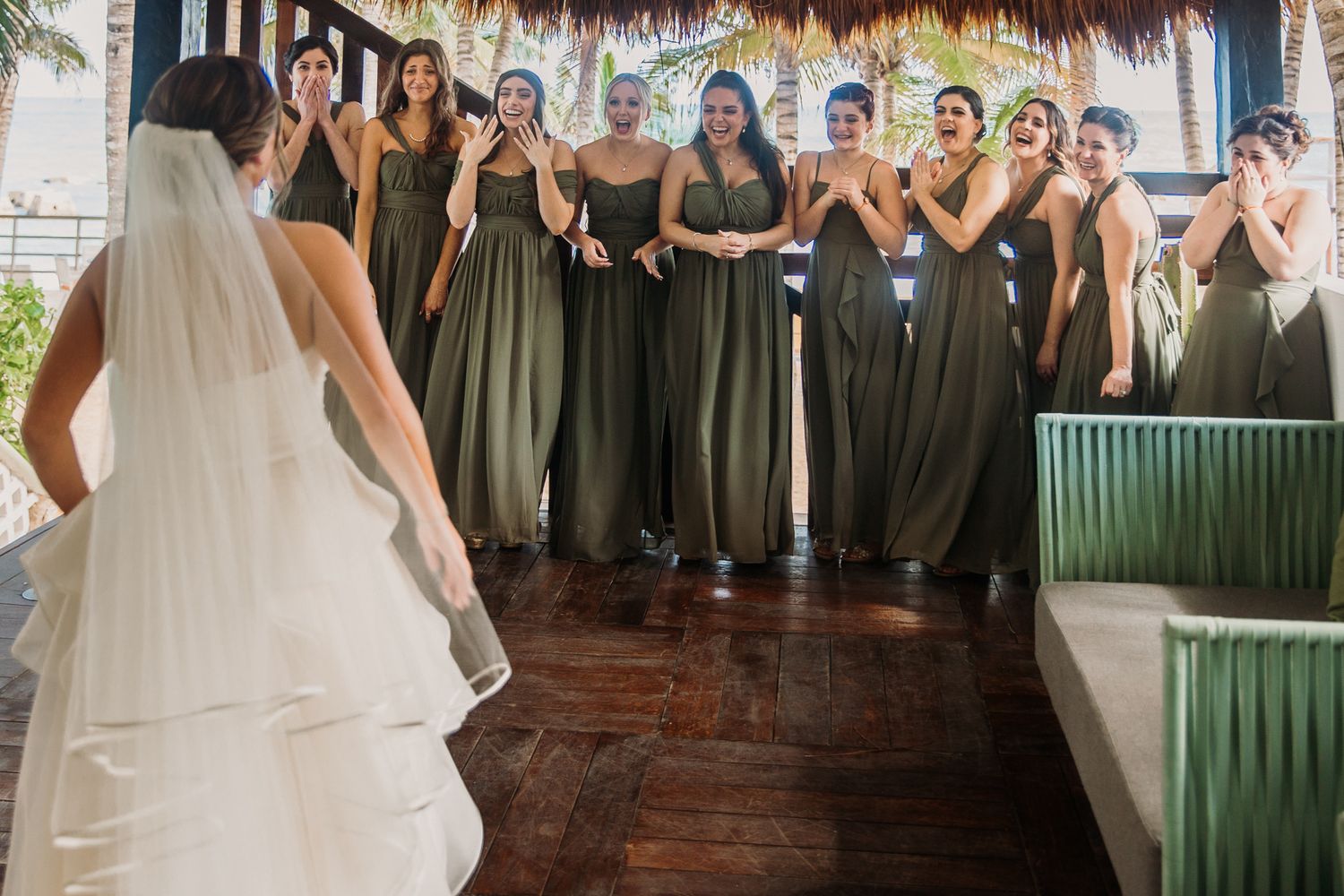Bridesmaids in sage green dresses and groomsmen in suits pose together at a rustic wedding venue. El Dorado Royale Wedding Photographer