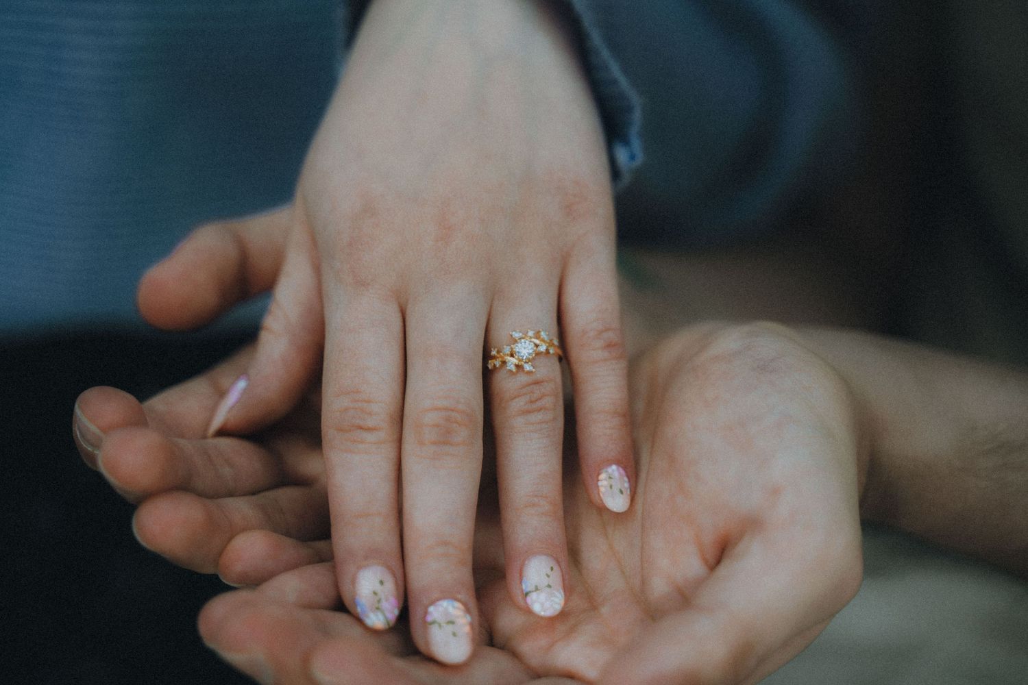An open book held by hands with sparkly nail polish against a dark background with Christmas lights.