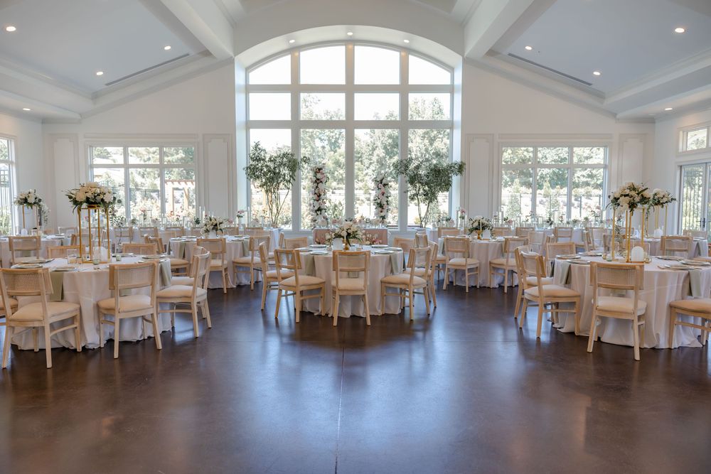 Elegant white wedding reception venue with coffered ceiling, large windows, and tables set for a formal celebration.