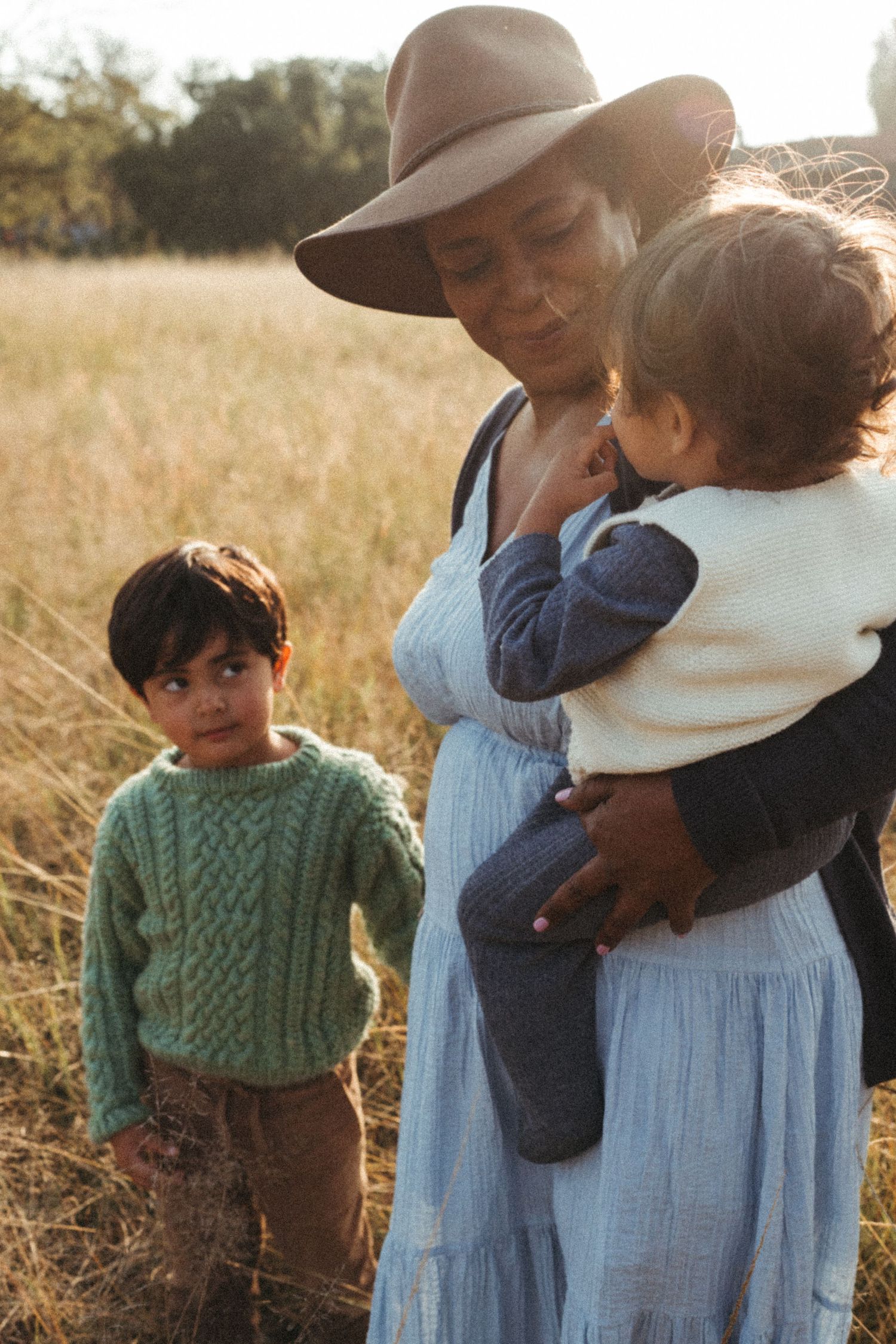 A heartwarming family moment captured in golden sunlight amidst a field of tall grass.