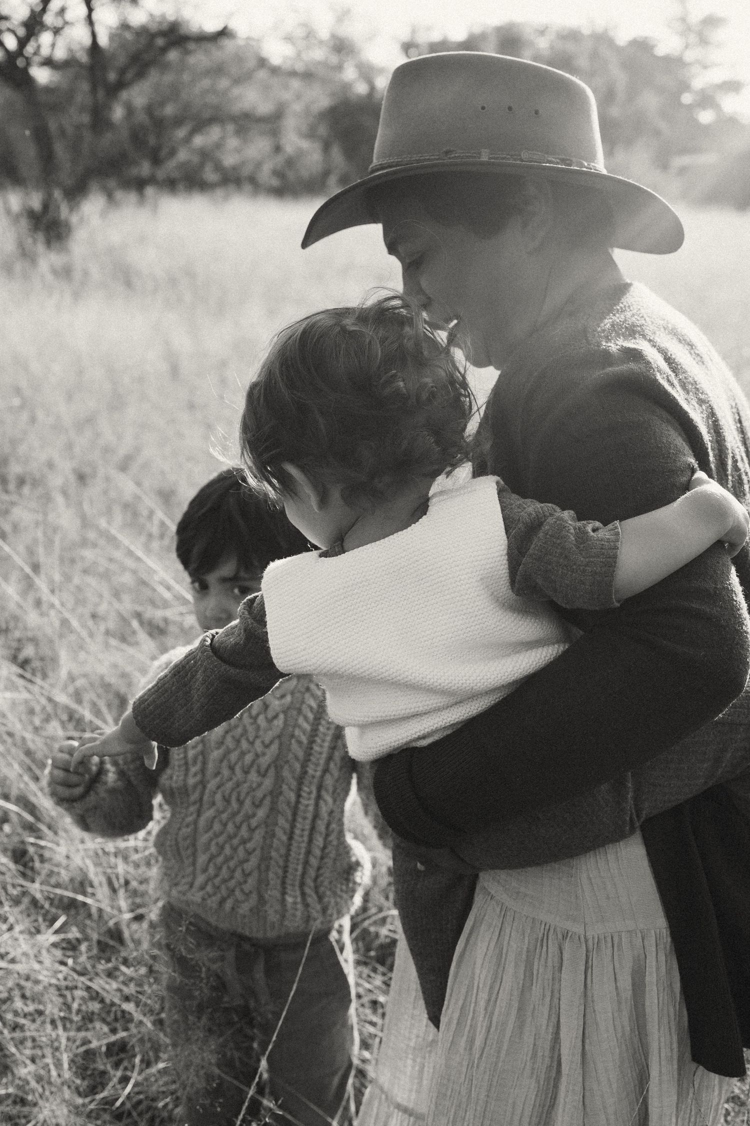 Black and white photograph showing tender embraces in a rustic outdoor setting.