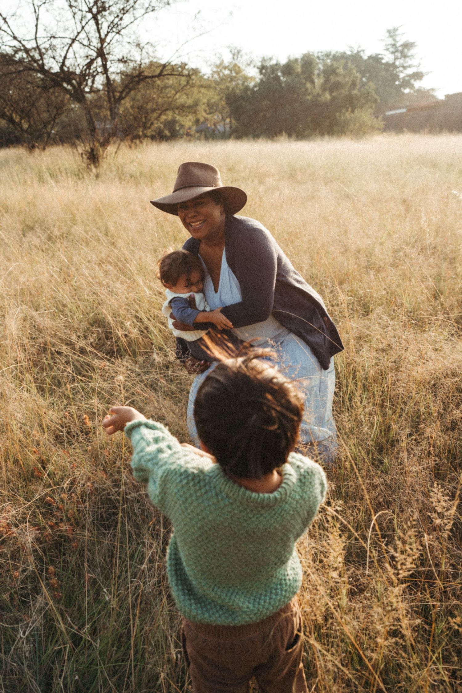 Intimate family moments photographed in warm evening light among tall grasses.