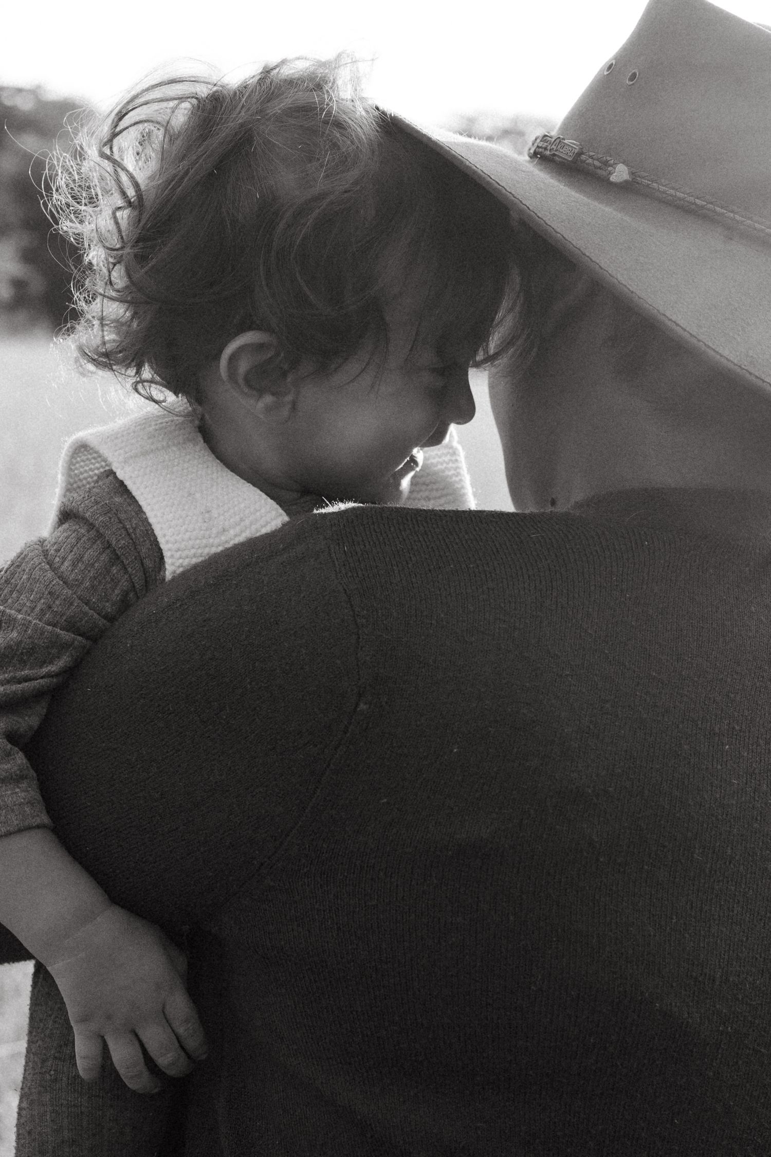 Black and white portrait of child resting on someone's shoulder.