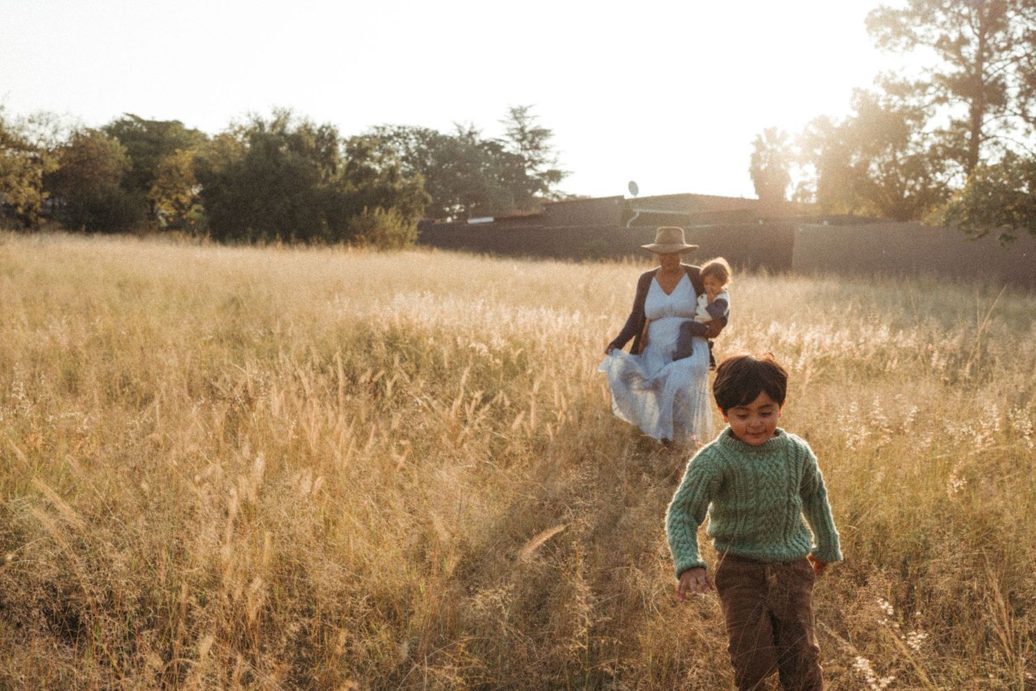 People walking through sun-drenched meadow during golden hour.
