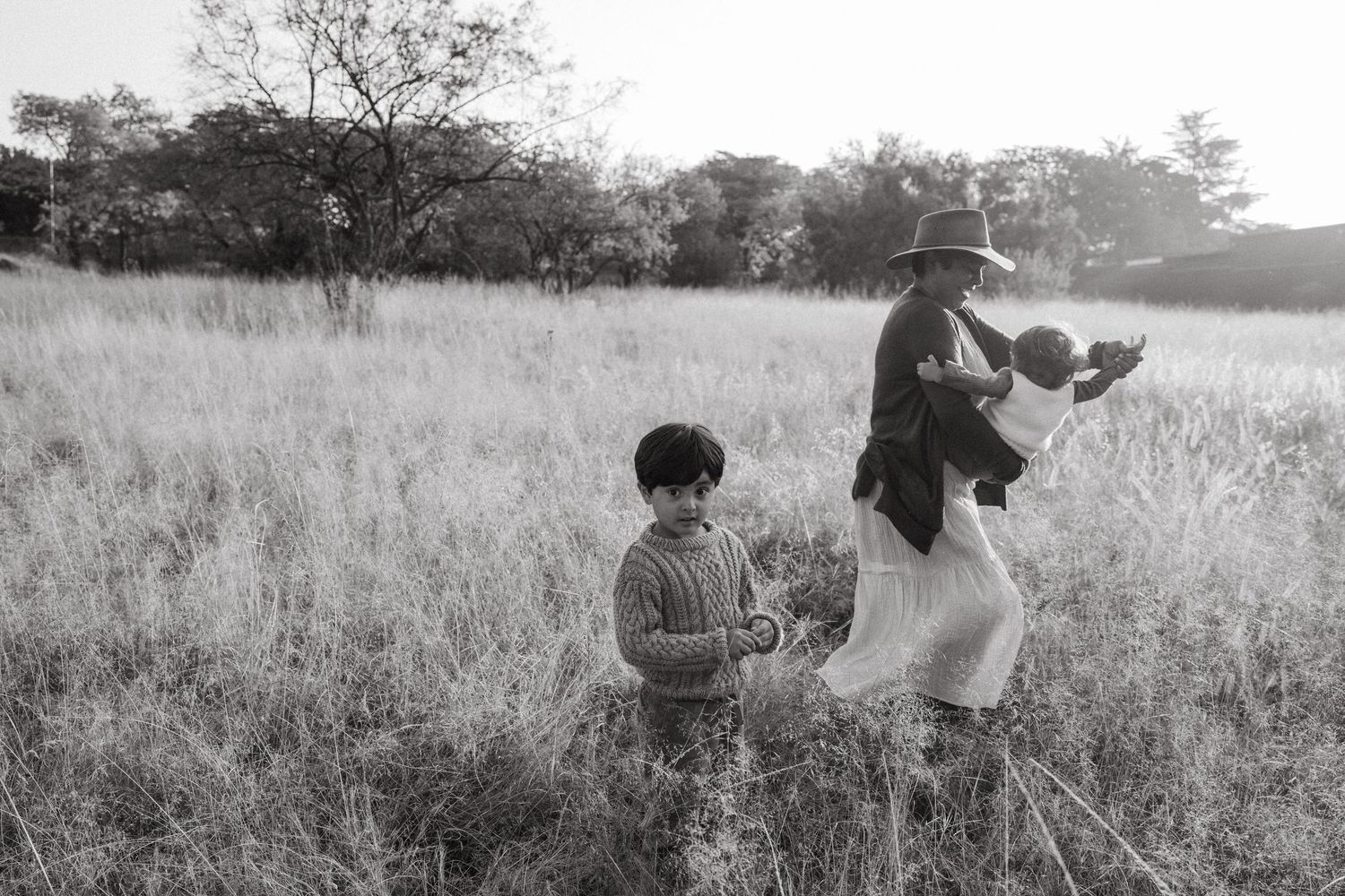 Black and white photo of people interacting in a grassy meadow.
