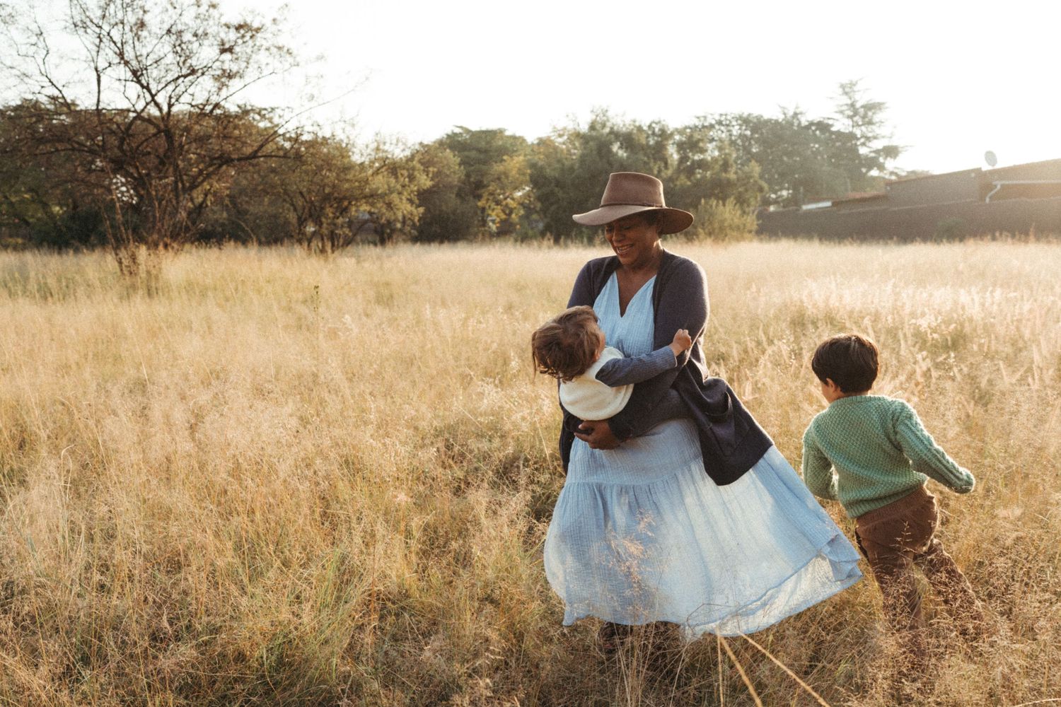 People sharing a tender moment in a sunlit field of tall grass.