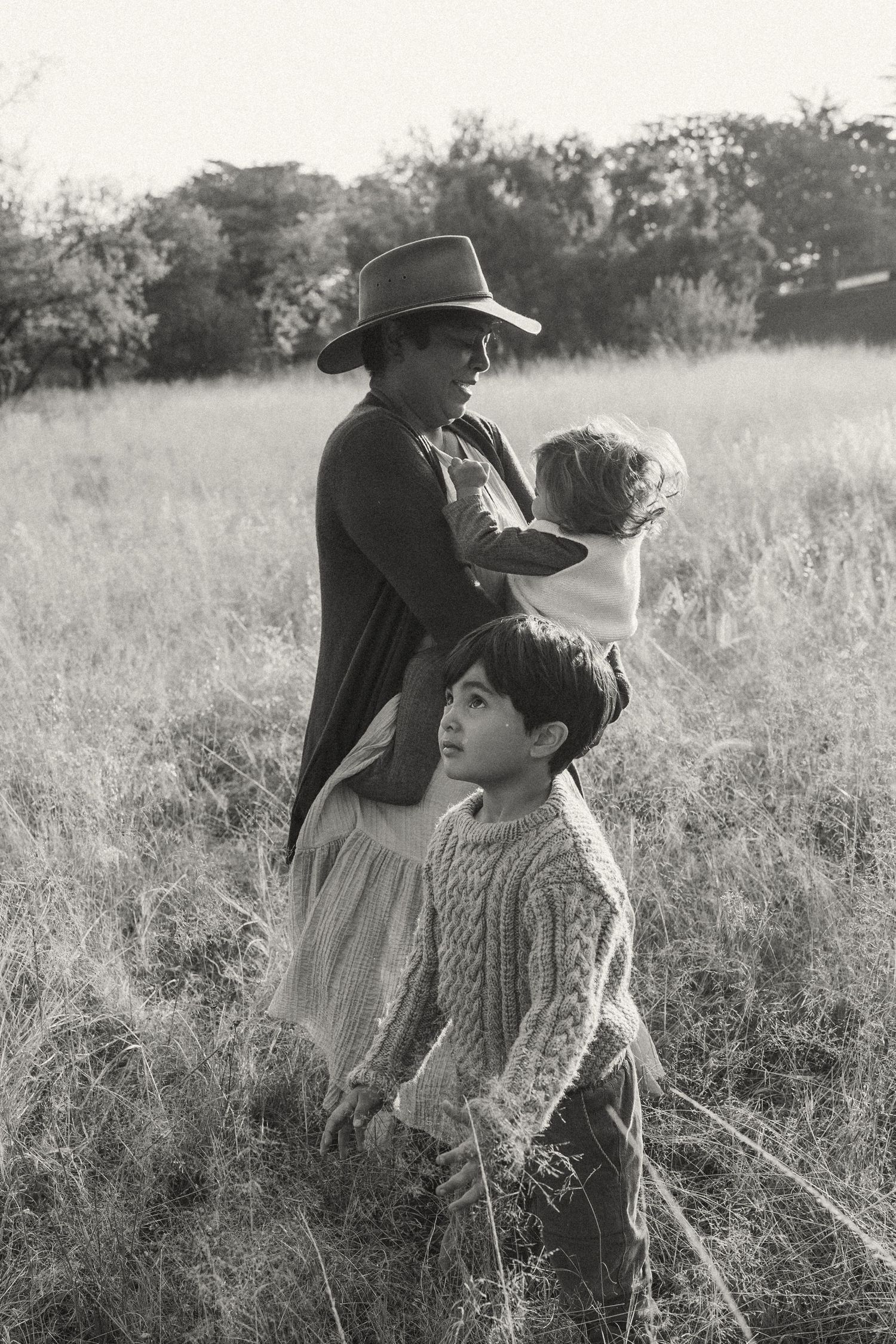 Black and white portrait of people gathered in a wild grass field.
