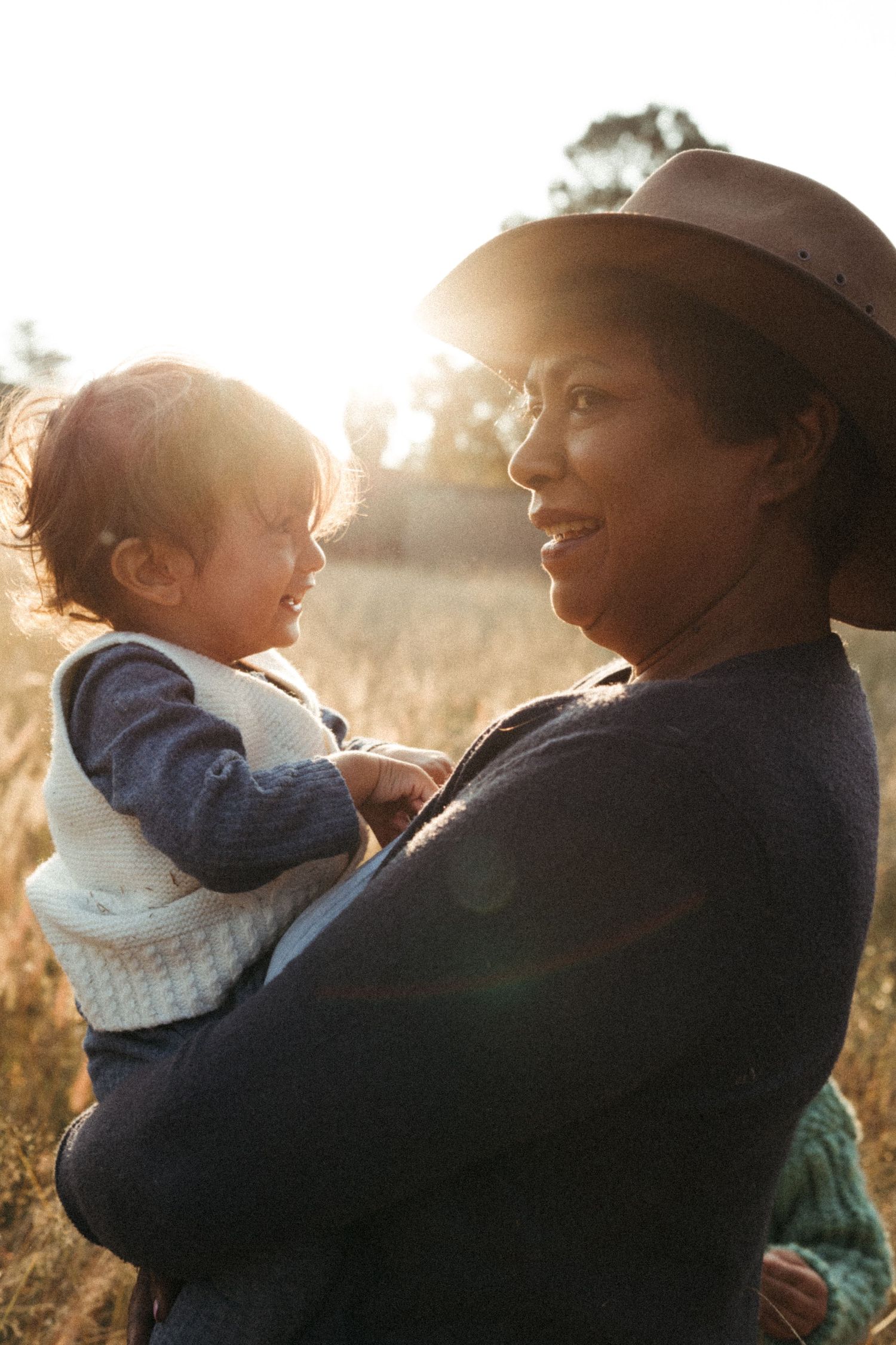 Two figures share a joyful moment together in warm sunlight against a natural outdoor setting.
