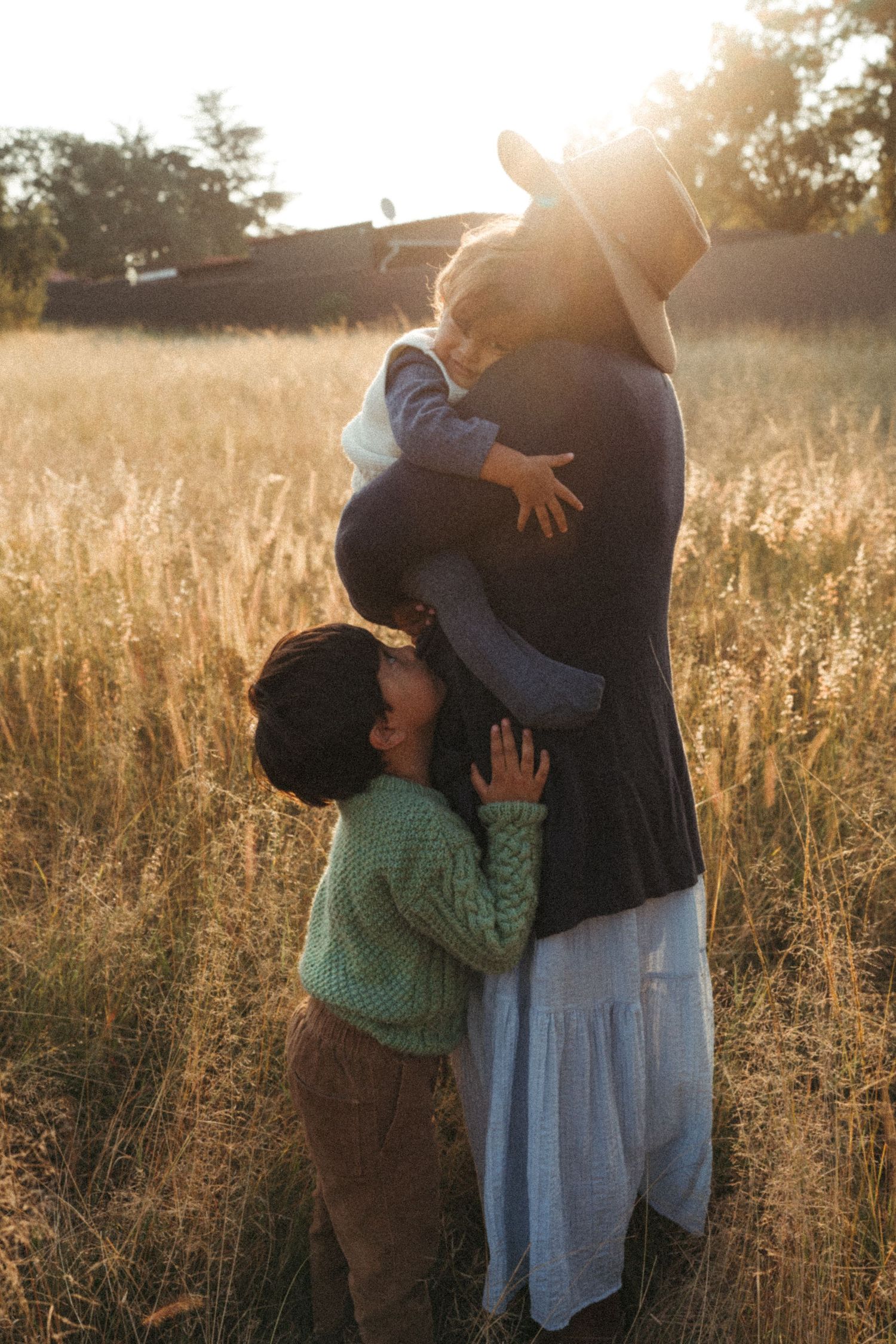 Tender moment between two people in a sunlit field with tall grass.