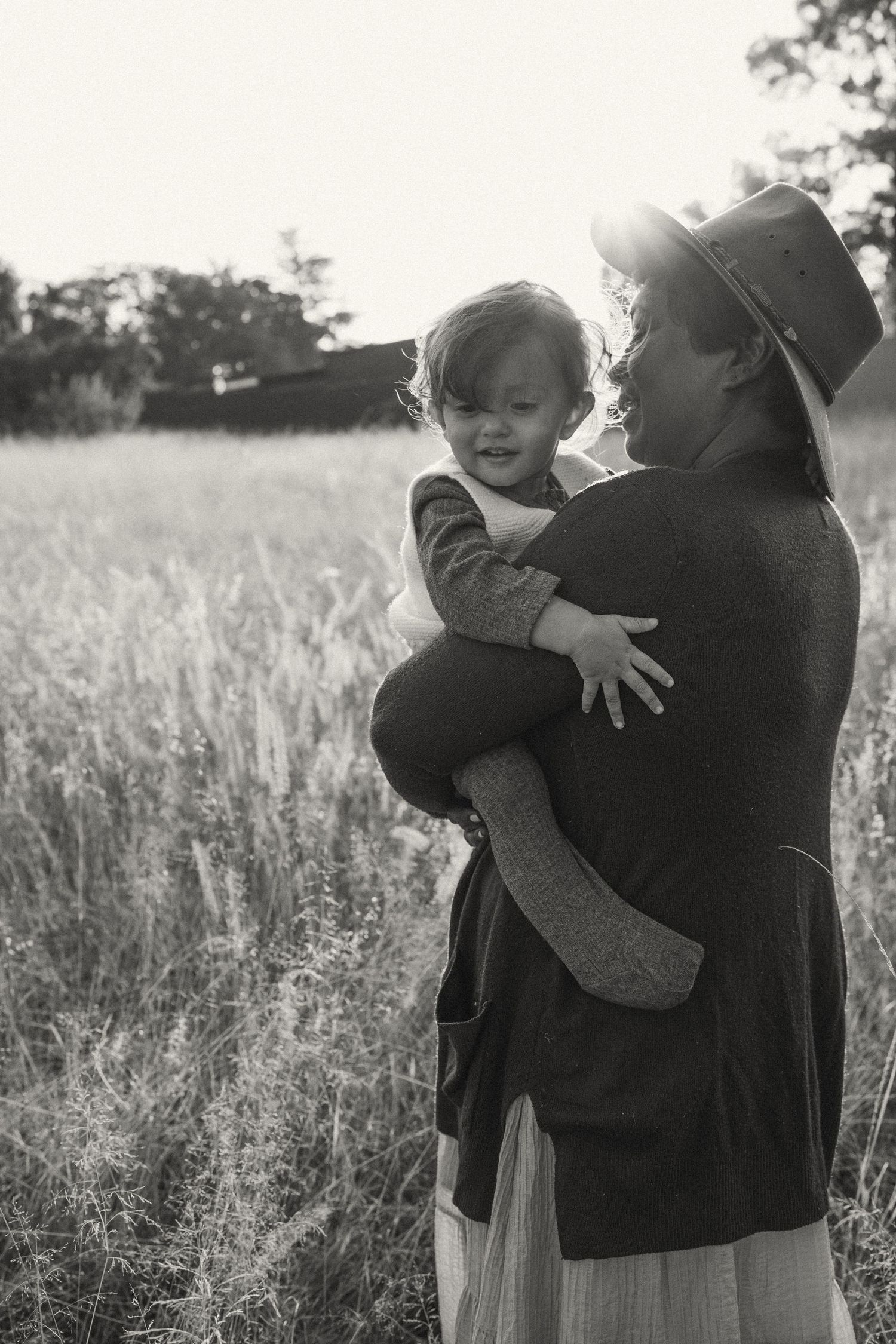 Black and white photo showing an intimate embrace amidst a field of tall grass.