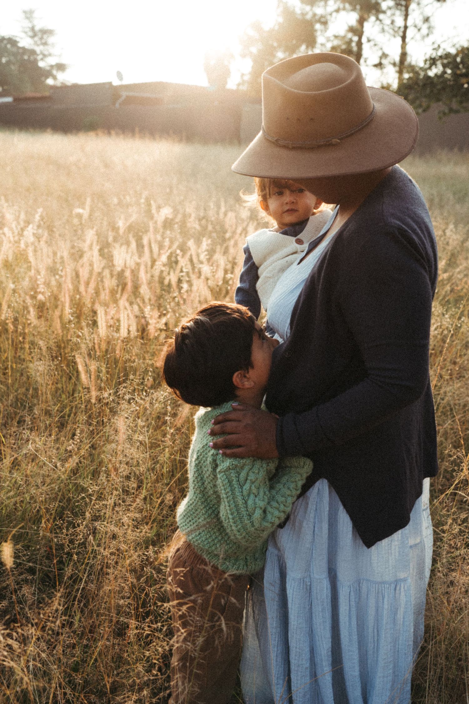 Sunlit portrait in a golden field showing a gentle embrace between two figures.