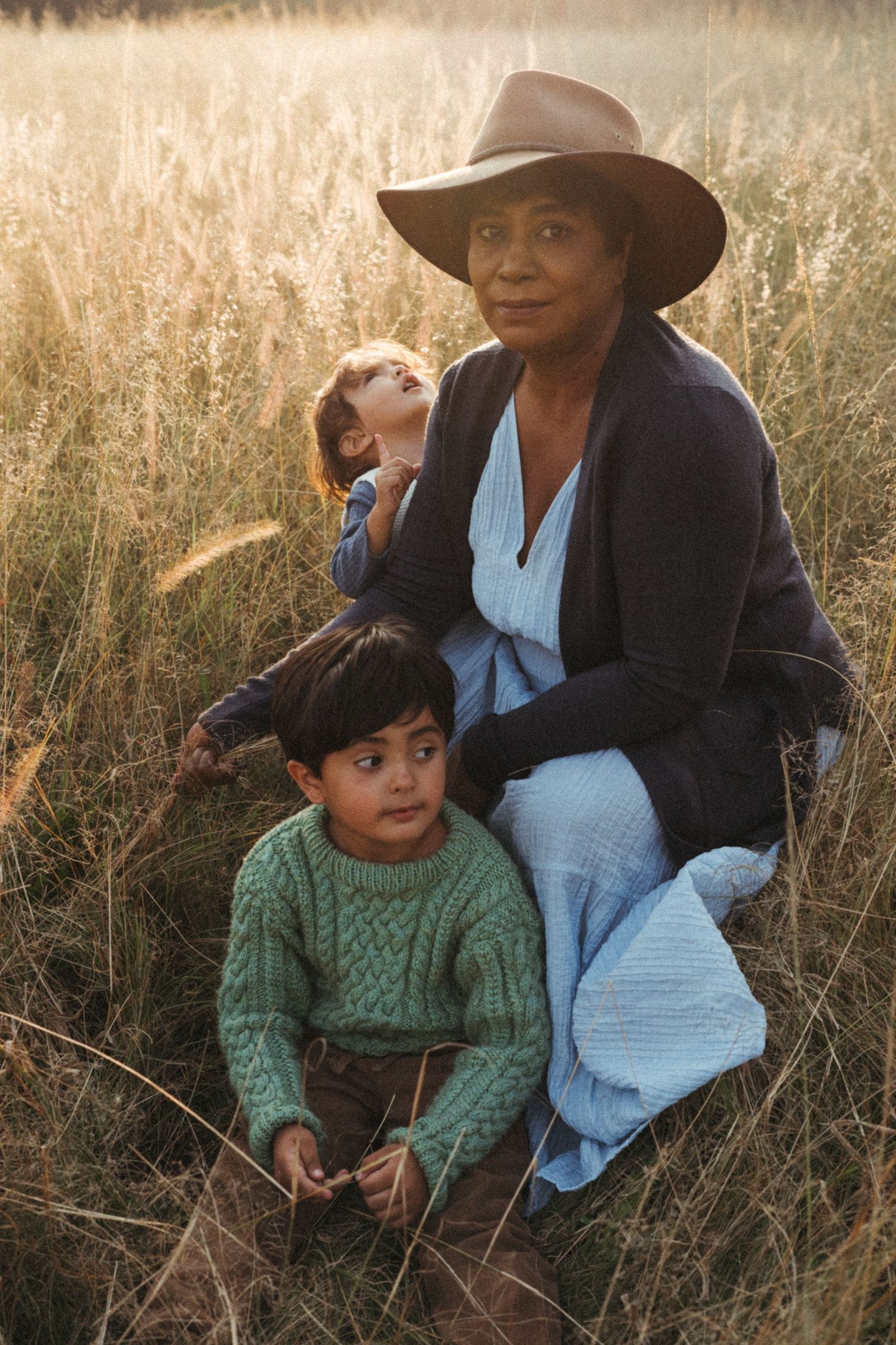 Candid outdoor portrait in warm light showing two people sitting among tall grass.
