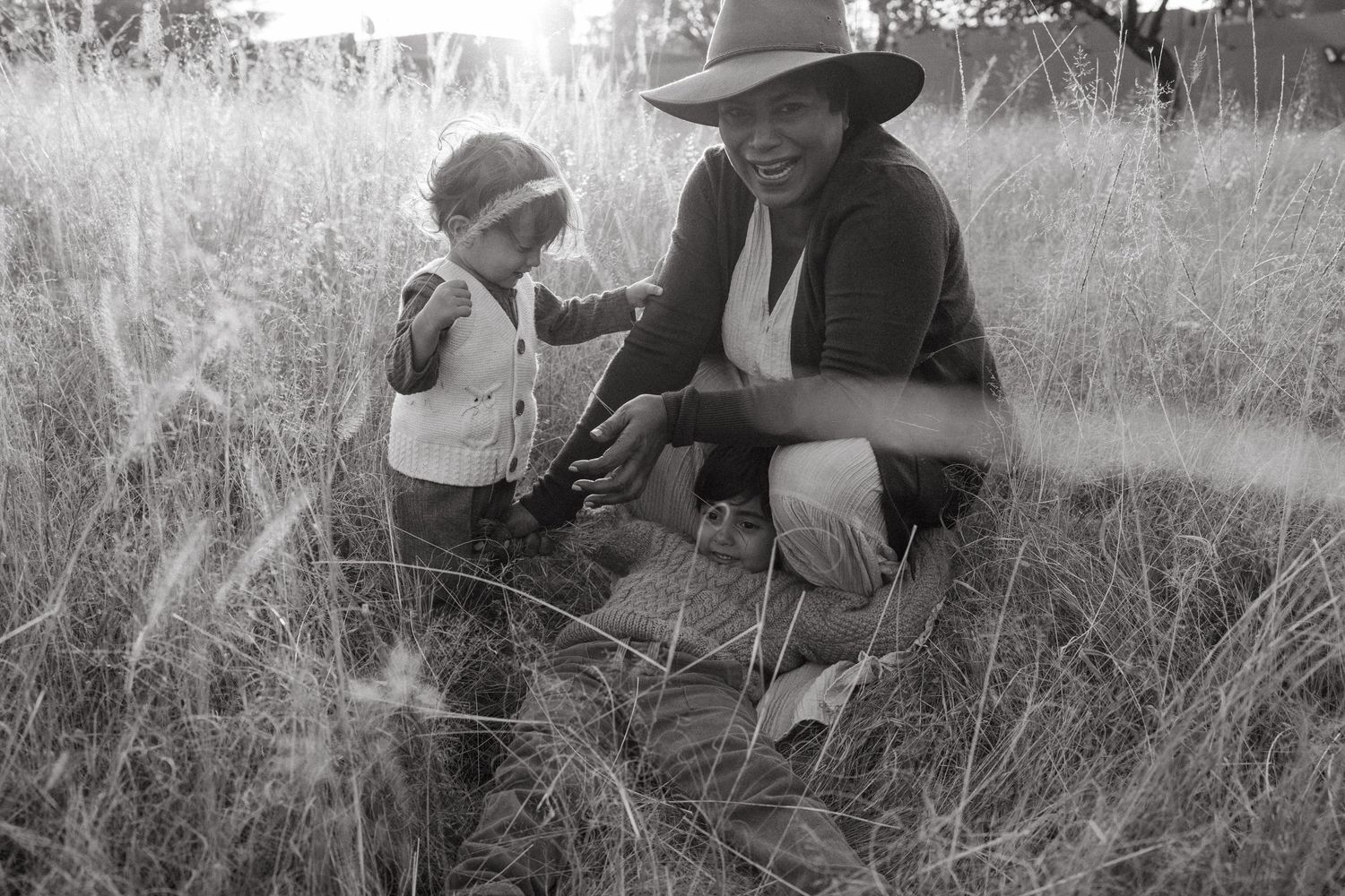 Black and white photograph of figures resting in a natural grass setting.
