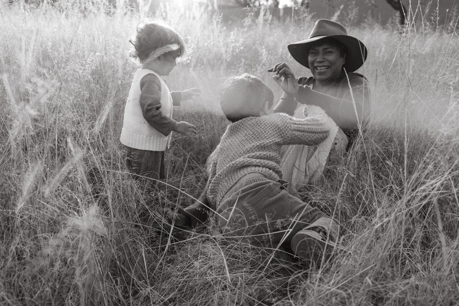 Black and white image capturing relaxed moments in a natural grass setting.