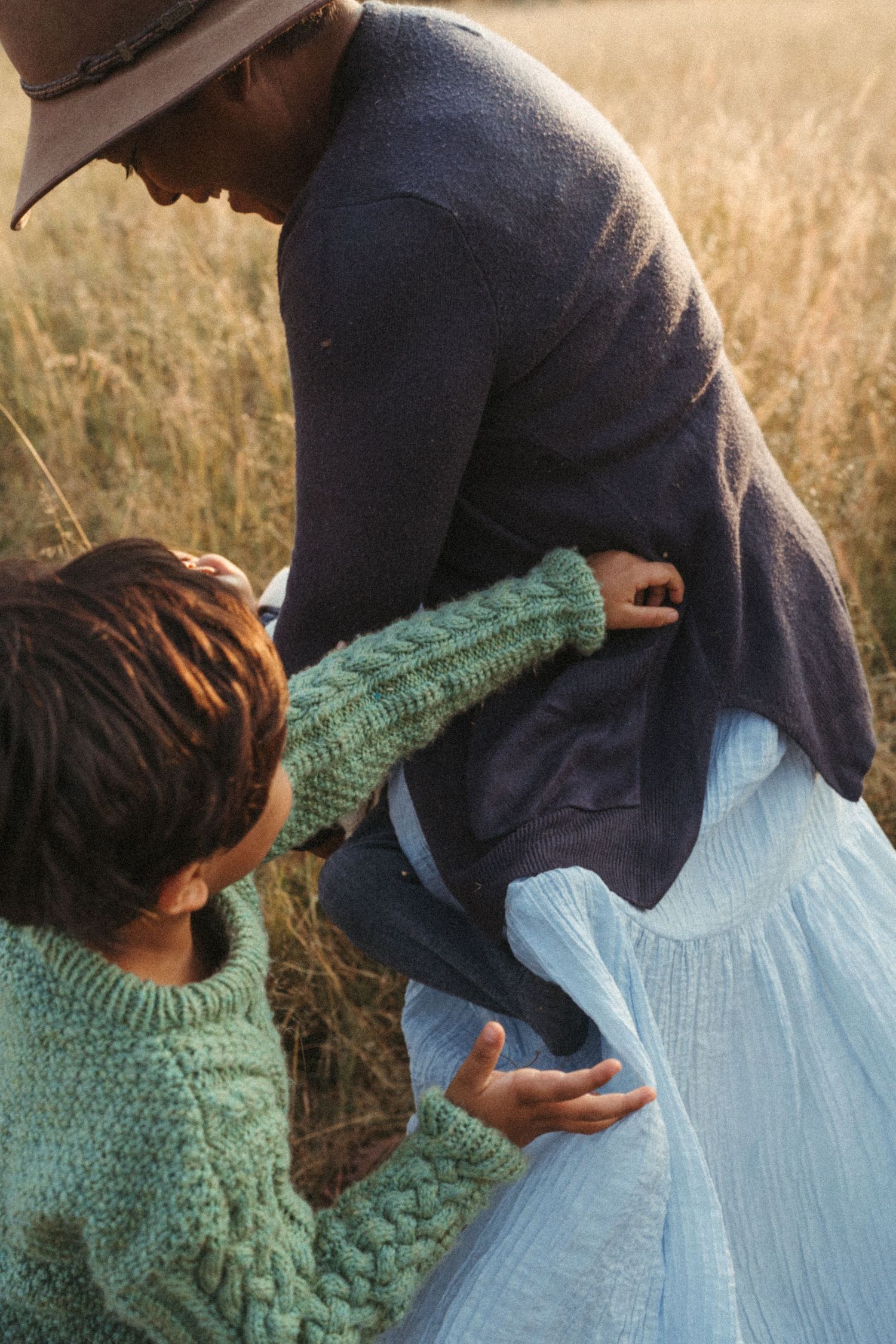 Close-up shots of intimate family moment in field with blue dress and mint sweater.
