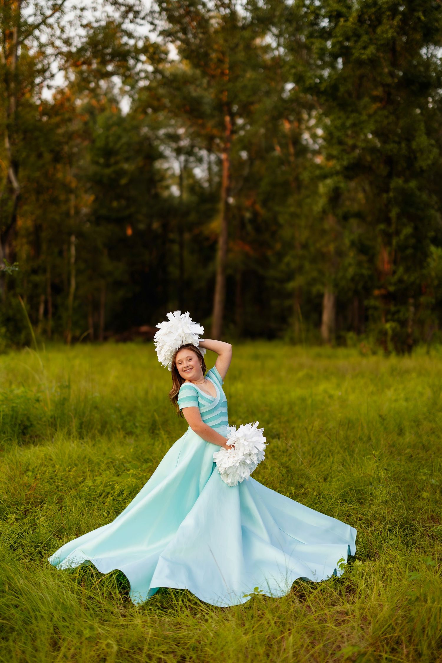 Flowing turquoise dress twirls gracefully in a sunlit meadow with white floral accents.