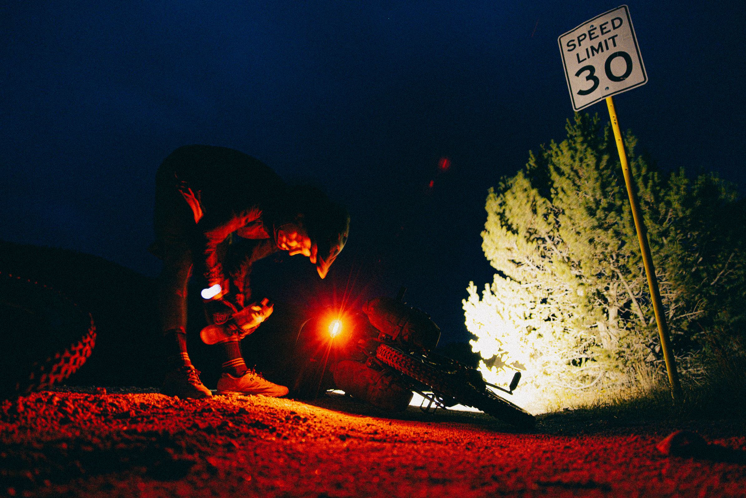 A sequence of red-lit nighttime trail biking photos showing a rider navigating through dark forest terrain.
