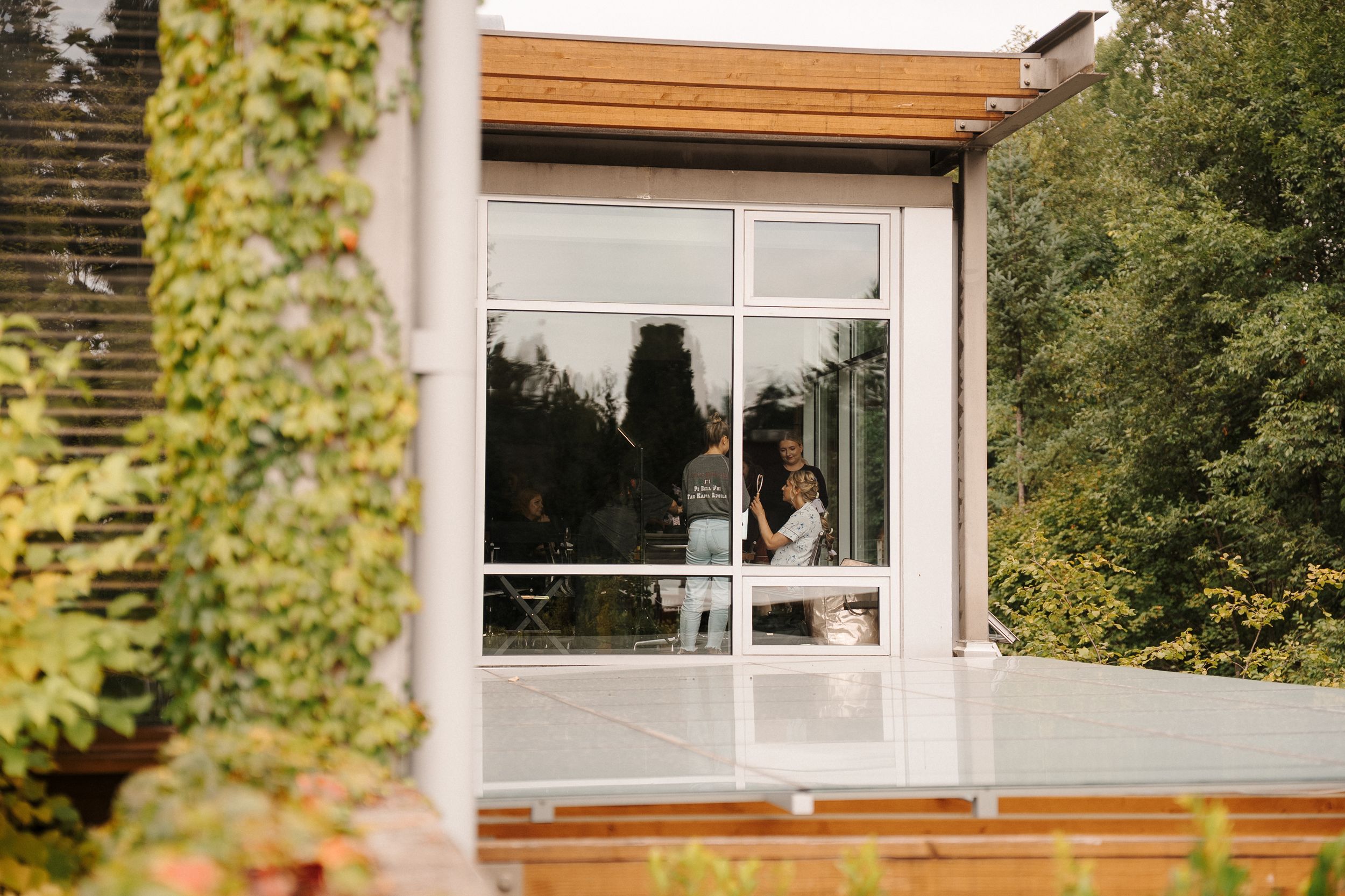 Modern wooden window frames and siding accent a contemporary home exterior with lush green foliage in the background.