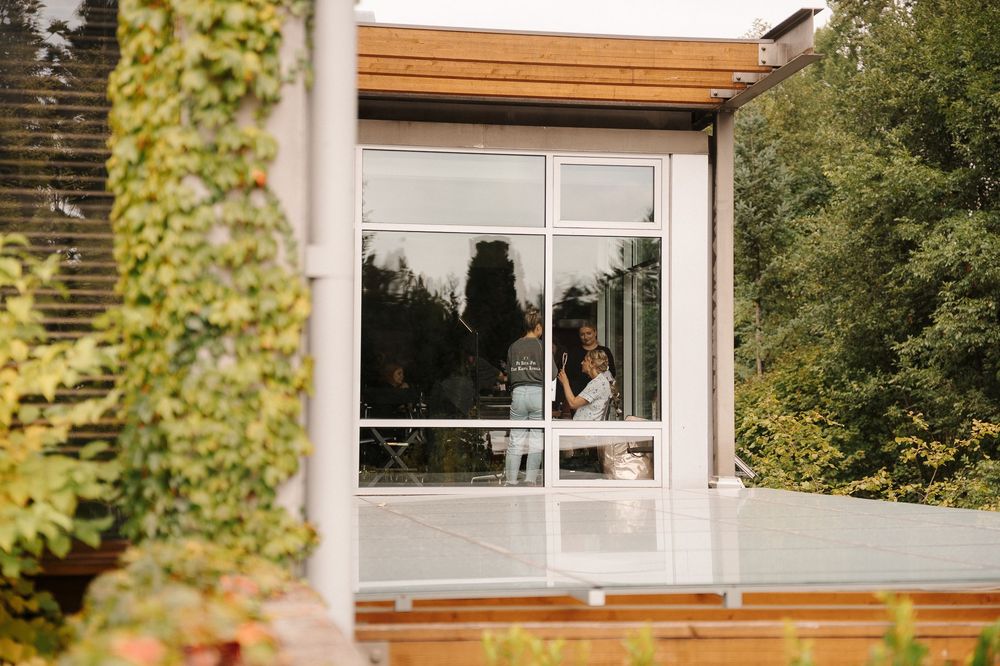 Modern wooden window frames and siding accent a contemporary home exterior with lush green foliage in the background.