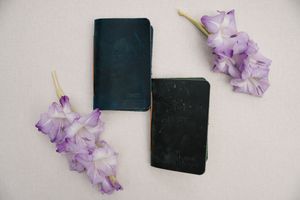 Purple wisteria flowers scattered around a black notebook on a light gray background.