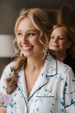 A person wearing a white and blue butterfly print robe smiles while getting ready.
