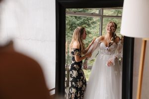 A touching moment between a bride in white and another person in a black floral dress sharing an emotional embrace.