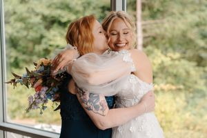 Two people share a joyful embrace during a wedding celebration in a bright, sunlit venue.